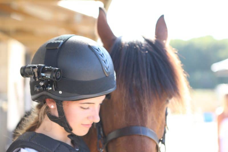 Woman wearing DC-1 Dual Lens Helmet Camera next to her horse