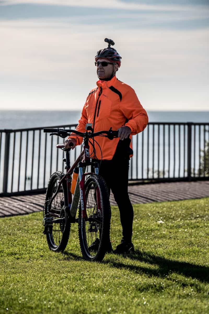 Man holding his bike, wearing the DC-1 Dual Lens Helmet Camera