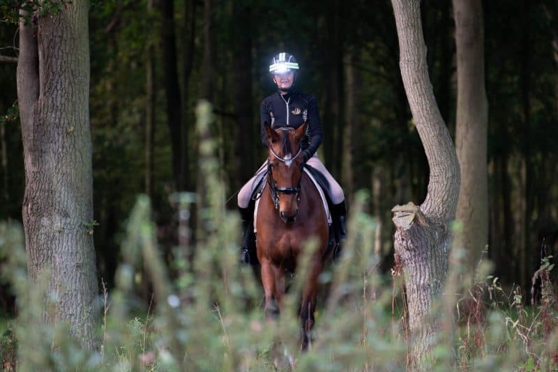 Woman ridig her horse through a forest with the CF-1 FRONT LIGHT attached to her camera
