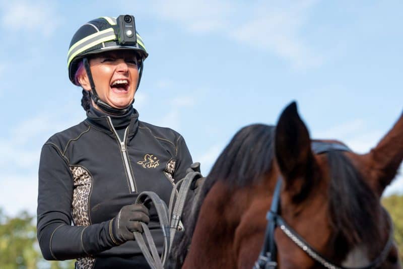 Woman laughing on her horse whilst wearing the Equestrian helmet camera CF-1 FRONT LIGHT