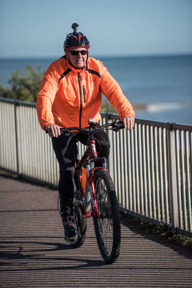 Man in orange cycling gear with DC-1 Dual Lens Helmet Camera attached