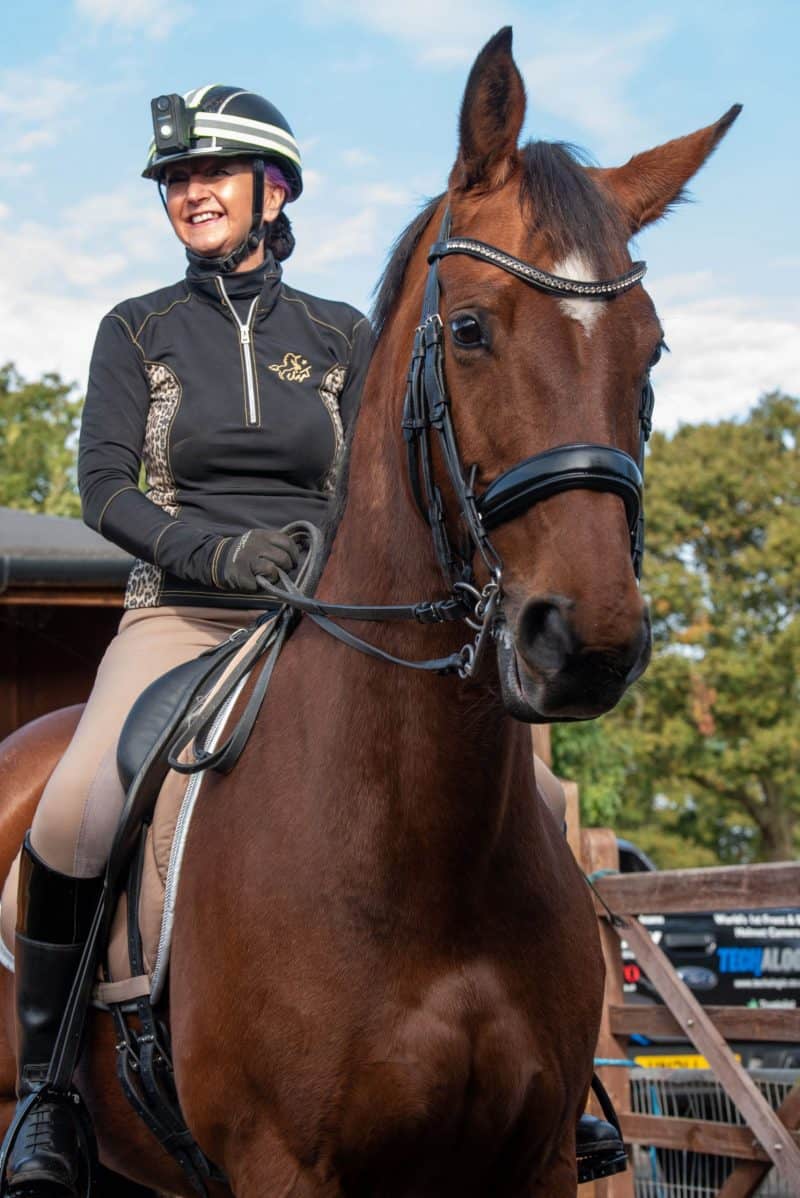 Woman smiling whilst sitting on her horse and wearing CF-1 FRONT LIGHT
