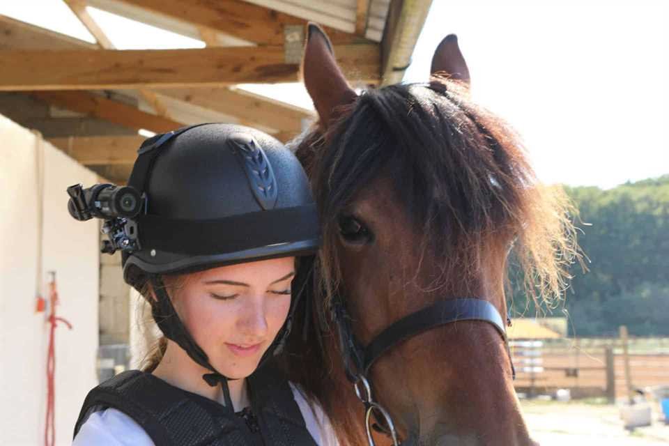 Horse rider wearing a camera beside a horse